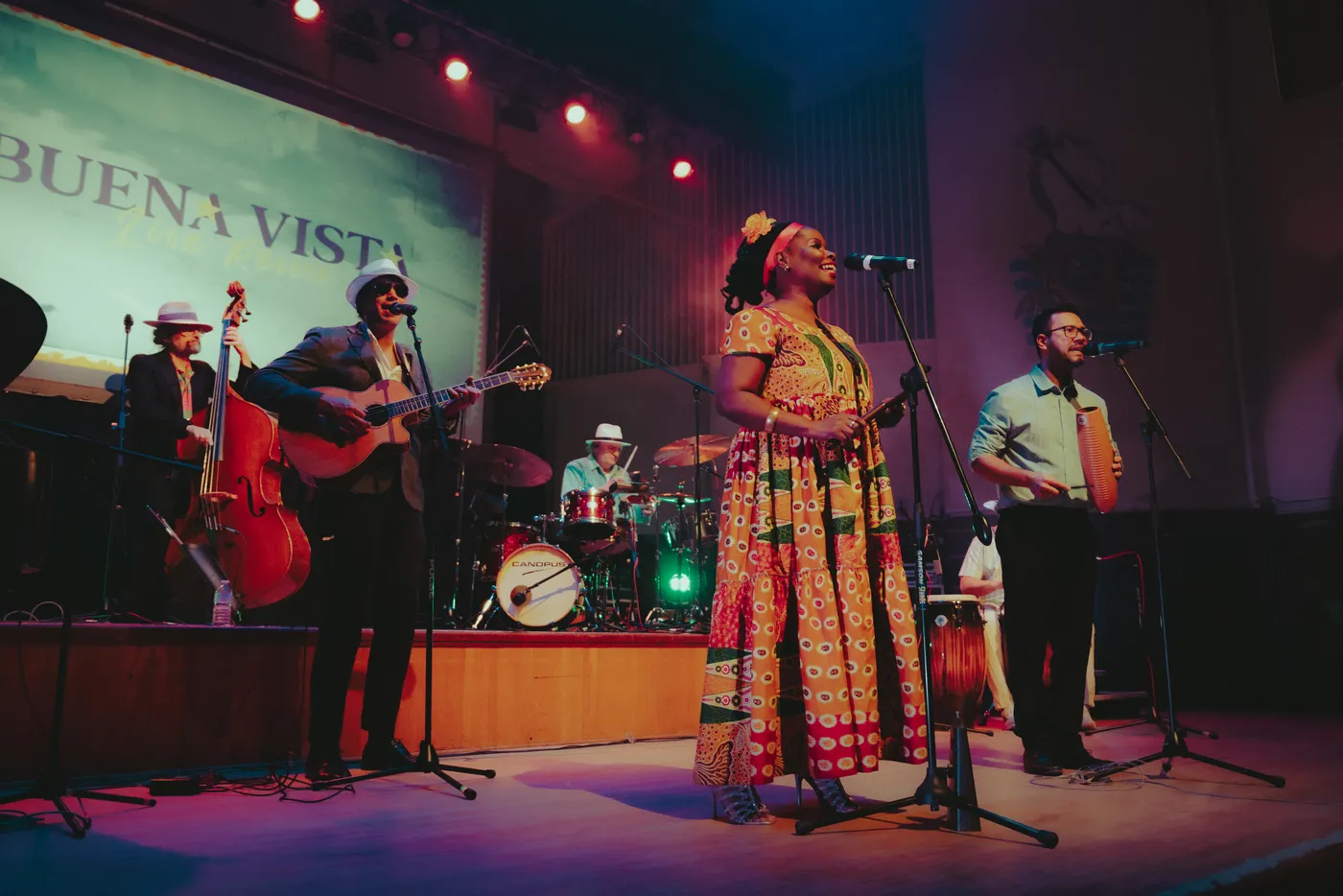 The full Buena Vista Live band on stage, with a singer in a patterned dress at the centre microphone