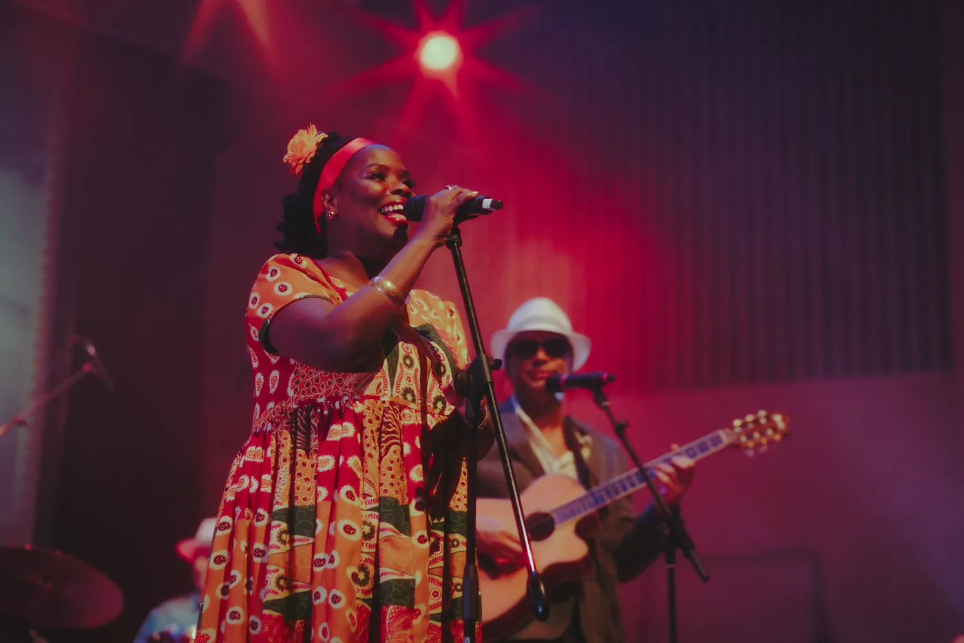 A singer from Buena Vista Live at the microphone, with a guitarist behind her
