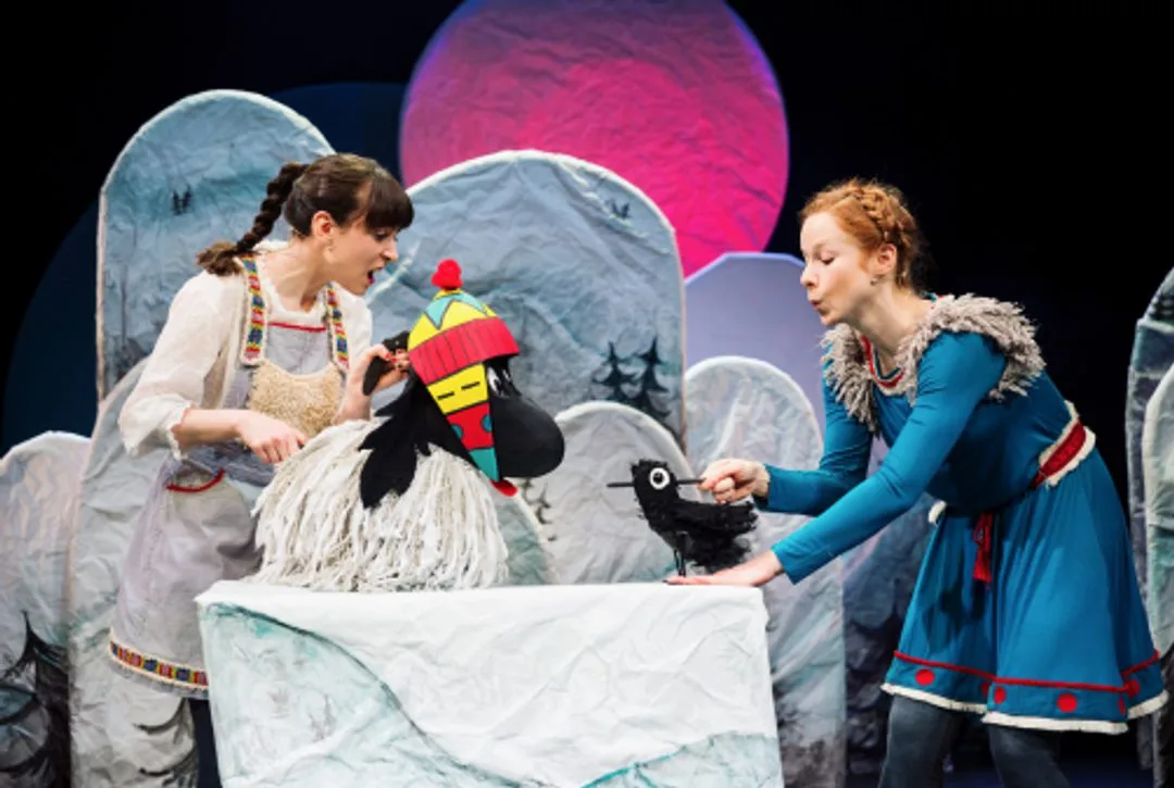 Three performers on stage, one playing an accordion and one a flute, in front of a painted mountain set