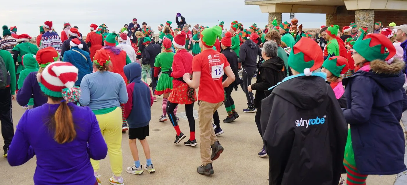 A large crowd in green and red elf hats gathered on Worthing promenade